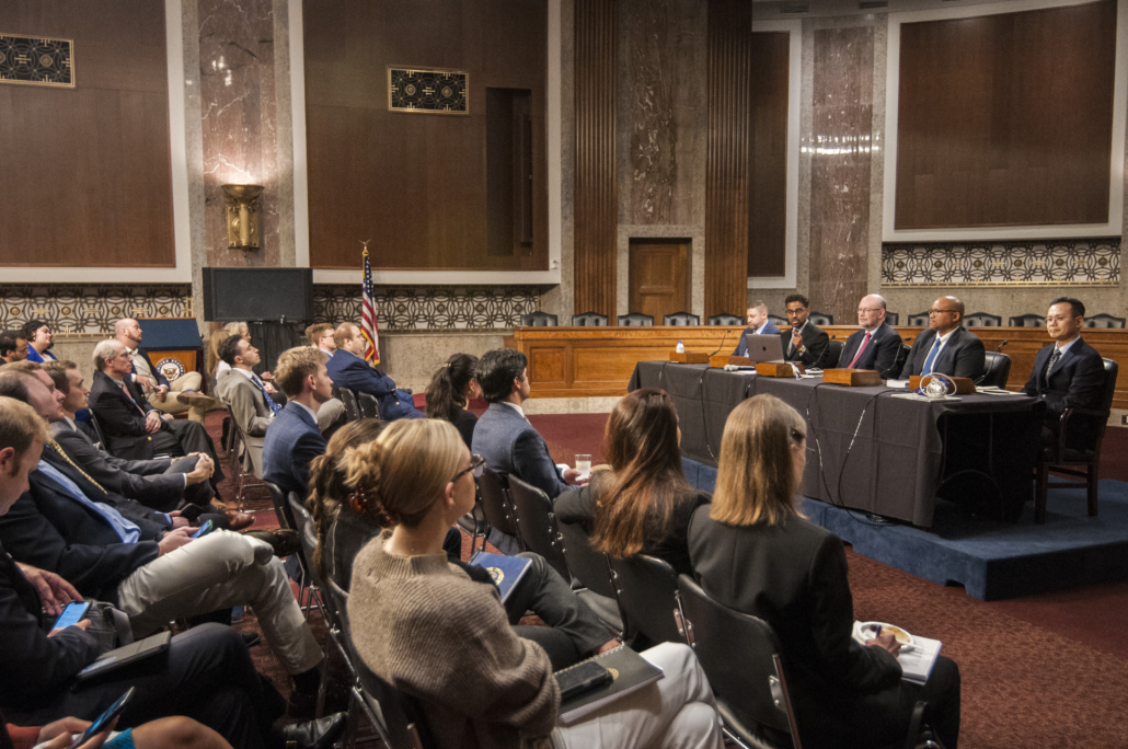 A panel of five experts at a table, with Dr. Balaprakash, second from the left, makes remarks to a large crowd of Senate staffers.